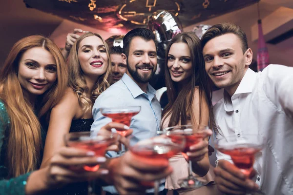 Os jovens divertem-se numa discoteca. Eles bebem coquetéis e se divertem . — Fotografia de Stock