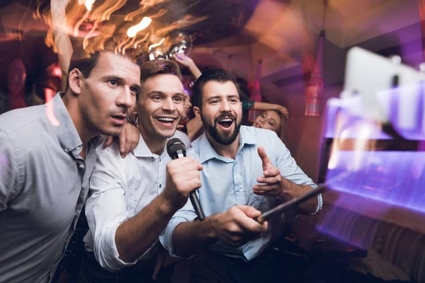 Három férfi énekelni egy karaoke klub. A fiatalok szórakozni egy szórakozóhely. Nagyon vidám, és mosolyog. — Stock Fotó