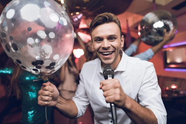 Die jungen Leute amüsieren sich in einem Nachtclub und singen Karaoke. Im Vordergrund ein Mann im weißen Hemd. — Stockfoto