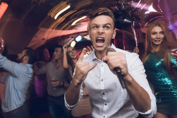 Egy férfi egy fehér inget énekel egy szórakozóhely. Ő birtokol egy mikrofonnal a kezében. — Stock Fotó