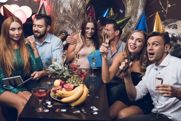 Die jungen Leute ruhen sich in einem angesagten Nachtclub aus. ein Mann im weißen Hemd und ein Mädchen im schwarzen Kleid singen. — Stockfoto