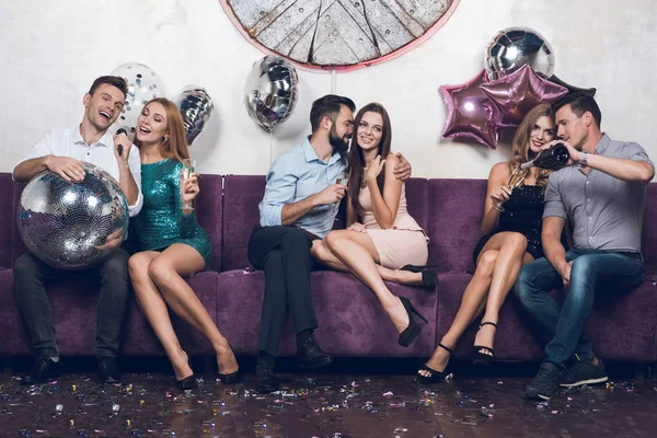 Los jóvenes descansan en parejas en un club nocturno. Beben champán y cantan canciones . — Foto de Stock