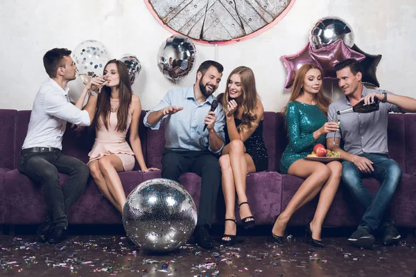 Los jóvenes descansan en parejas en un club nocturno. Beben champán y cantan canciones . — Foto de Stock