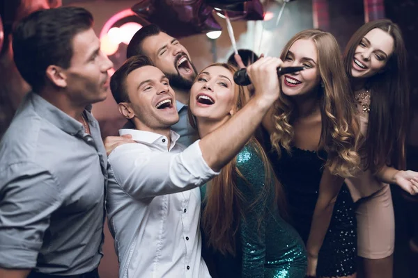 Los jóvenes del club bailan y cantan. Un hombre con una camisa blanca sostiene un micrófono y canta . — Foto de Stock