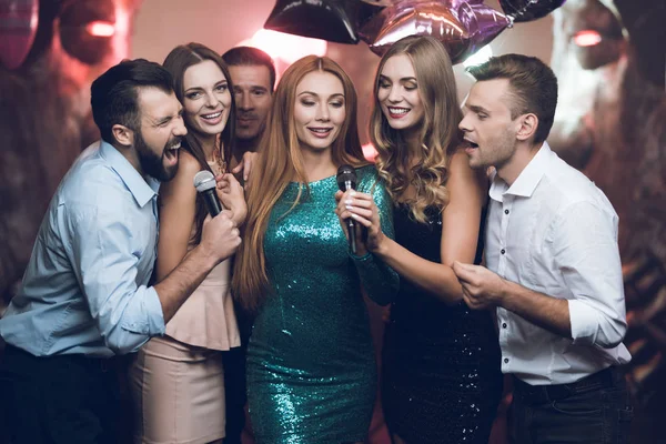 Kulüp genç insanlar dans ve şarkı. Beyaz gömlekli bir mikrofon tutan ve şarkı söyleyen biri.