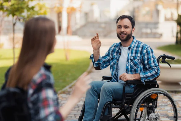 一对夫妇在轮椅上的残疾人在公园相遇。一个男人在问候一个女人. — 图库照片
