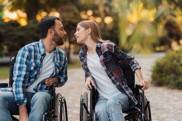 Ein paar Invaliden im Rollstuhl trafen sich im Park. Sie fühlen sich zu einem Kuss hingezogen. — Stockfoto
