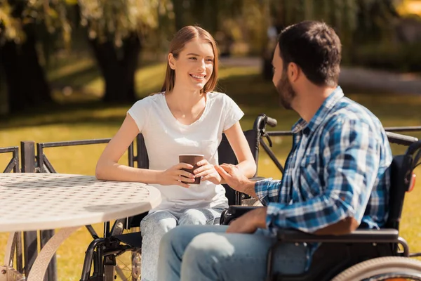 Un par de personas con discapacidad están tomando café mientras están sentados en una mesa en el parque . —  Fotos de Stock