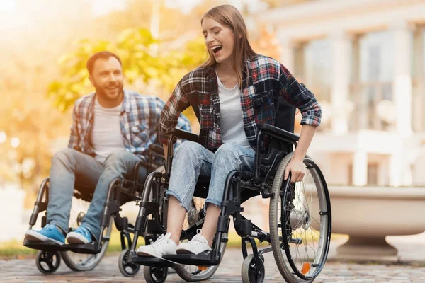 Um homem e uma mulher em cadeiras de rodas andam pelo parque. Eles organizaram uma corrida em cadeiras de rodas . — Fotografia de Stock