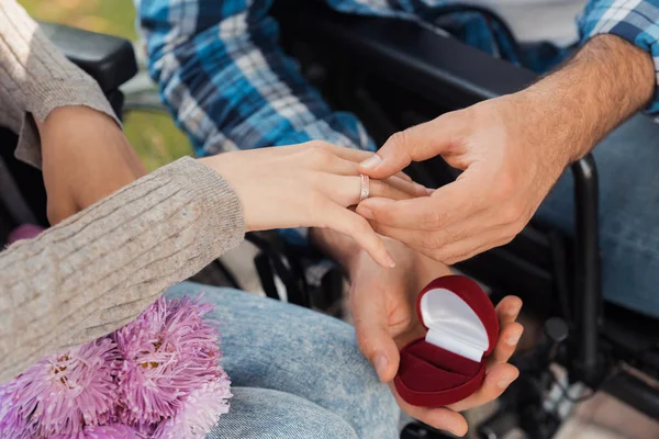Un homme et une femme en fauteuil roulant se sont rencontrés dans le parc. Un homme met une bague sur le doigt d'une femme . — Photo