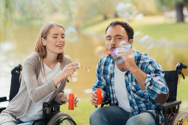 В парке встретились мужчина и женщина в инвалидных колясках. Они начинают пузыри . — стоковое фото
