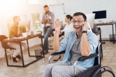 Özürlü tekerlekli sandalyedeki ofiste çalışıyor. Smartphone üzerinde konuşuyor.