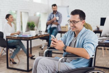 Özürlü tekerlekli sandalyedeki ofiste çalışıyor. O onun smartphone kullanır.