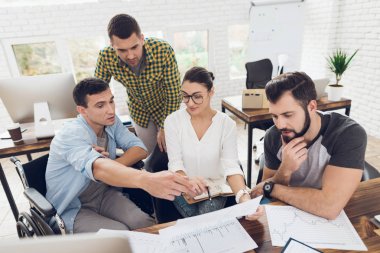 Ofis çalışanları ve tekerlekli sandalye bir kişi çalışma sorunlarını tartışmak. Onlar parlak bir ofiste çalışmak.
