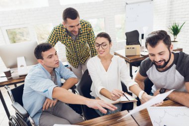 Ofis çalışanları ve tekerlekli sandalye bir kişi çalışma sorunlarını tartışmak. Onlar parlak bir ofiste çalışmak.