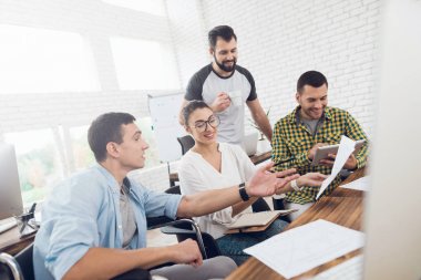 Ofis çalışanları ve tekerlekli sandalye bir kişi çalışma sorunlarını tartışmak. Onlar parlak bir ofiste çalışmak.