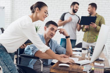 Tekerlekli sandalyede bir adam bir kız ile bir konuşma yapıyor. Onlar parlak bir ofiste çalışıyoruz.