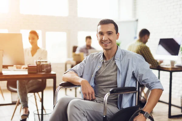 Disabled person in the wheelchair works in the office. He is posing for the camera.