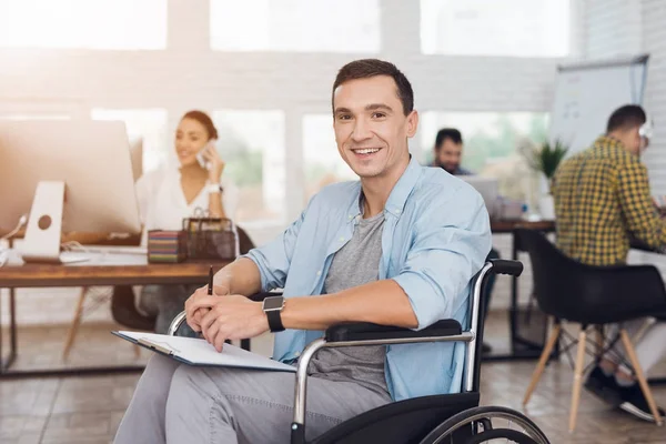 La persona disabile sulla sedia a rotelle lavora in ufficio. Scrive su un tablet per i giornali. . — Foto Stock