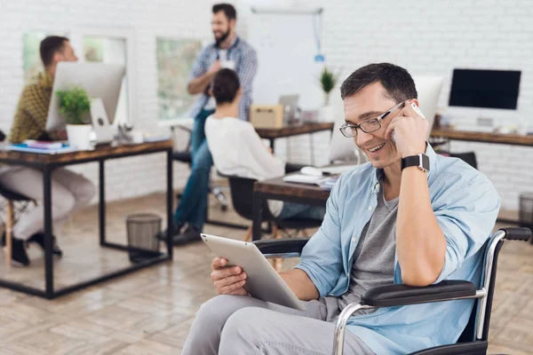 La persona con discapacidad en silla de ruedas trabaja en la oficina. Habla por teléfono inteligente . — Foto de Stock