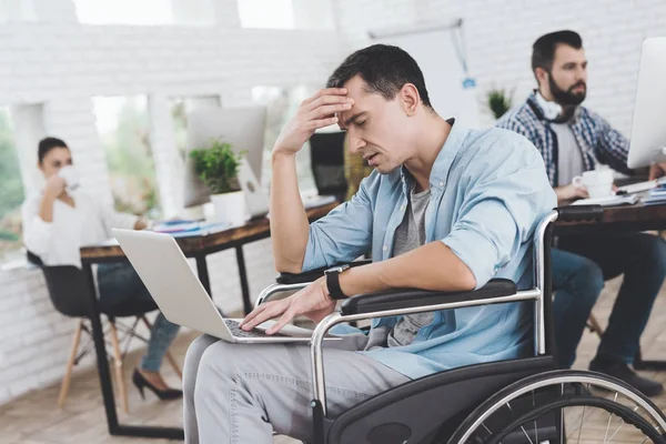 La persona disabile sulla sedia a rotelle lavora in ufficio. E 'seduto pensieroso . — Foto Stock