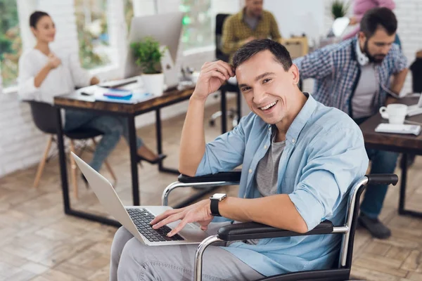 Osoba niepełnosprawna na wózku pracuje w biurze na laptopie. — Zdjęcie stockowe