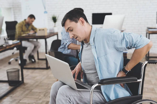 Disabled person in the wheelchair works in the office. He feel desease.