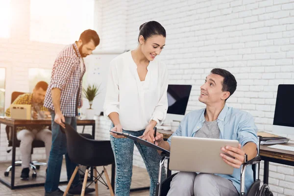 Bir kağıt tablet belgeleri imzalamak için bir tekerlekli sandalyede bir adam bir kız veriyor.