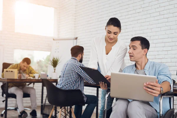 Een meisje geeft een man in een rolstoel te ondertekenen van documenten in een papier-tablet. — Stockfoto