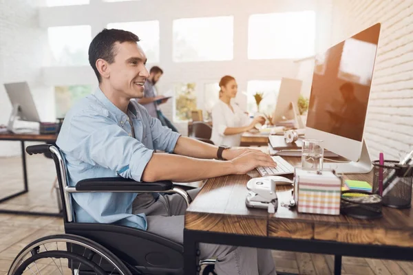 La persona disabile sulla sedia a rotelle lavora in ufficio al computer . — Foto Stock