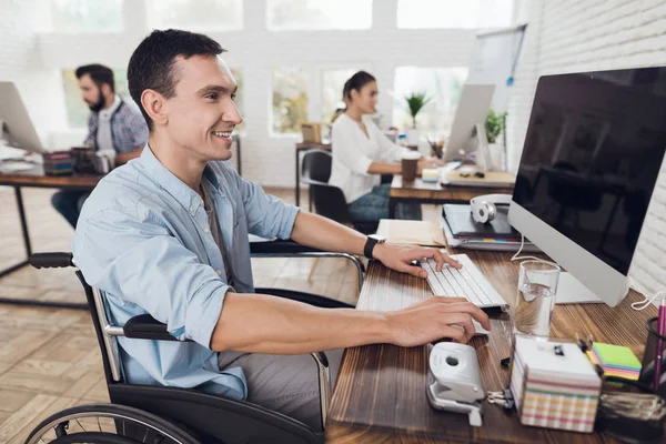Funktionshindrad person i rullstol fungerar på kontoret vid datorn. — Stockfoto