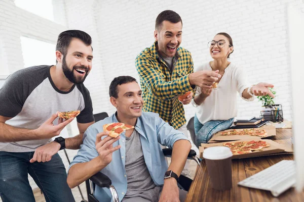 Kantoormedewerkers en man in een rolstoel kijken naar het computerscherm en lach. — Stockfoto