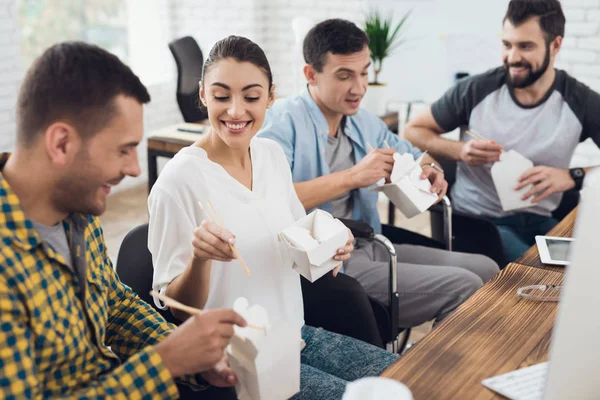 Bir grup genç insanlar ve tekerlekli sandalyeye mahkum adam konuşuyor ve Tay yemek yeme. Parlak bir ofiste olduklarını
