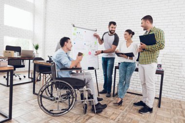 Office workers and man in a wheelchair discussing business moments while working in a modern office. clipart