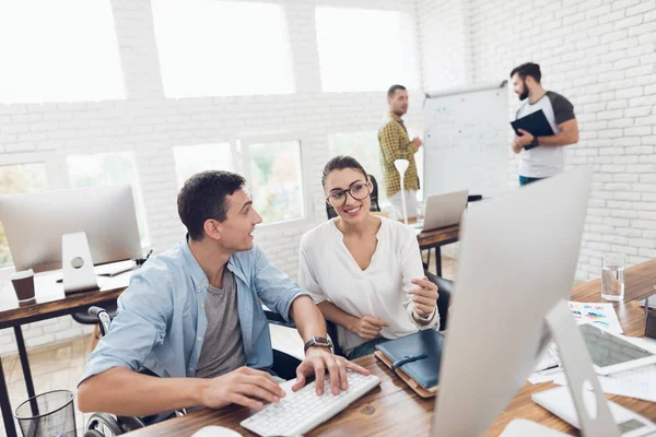 En mann i rullestol snakker med en jente. De jobber på et lysende kontor. . – stockfoto