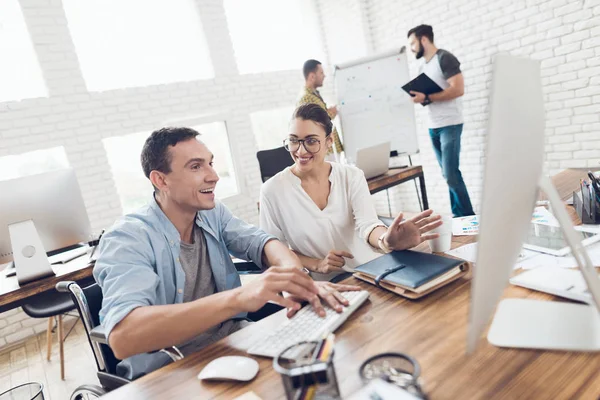 En mann i rullestol snakker med en jente. De jobber på et lysende kontor. . – stockfoto