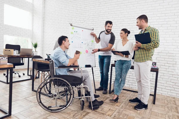 Lavoratori d'ufficio e uomo in sedia a rotelle discutono di momenti di lavoro mentre lavorano in un ufficio moderno . — Foto Stock