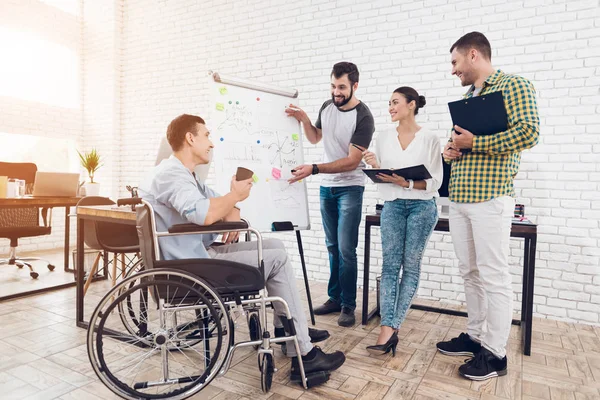 Lavoratori d'ufficio e uomo in sedia a rotelle discutono di momenti di lavoro mentre lavorano in un ufficio moderno . — Foto Stock