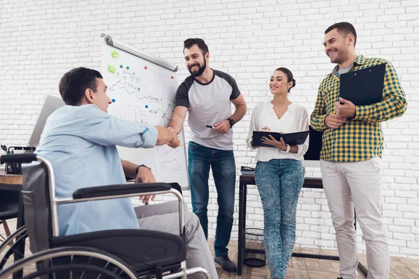 Ofis çalışanları ve modern bir ofiste çalışırken iş anlar tartışırken tekerlekli sandalyedeki adam.