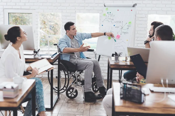 Lavoratori d'ufficio e uomo in sedia a rotelle discutono di momenti di lavoro in un ufficio moderno . — Foto Stock
