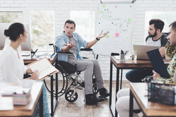 Lavoratori d'ufficio e uomo in sedia a rotelle discutono di momenti di lavoro in un ufficio moderno . — Foto Stock