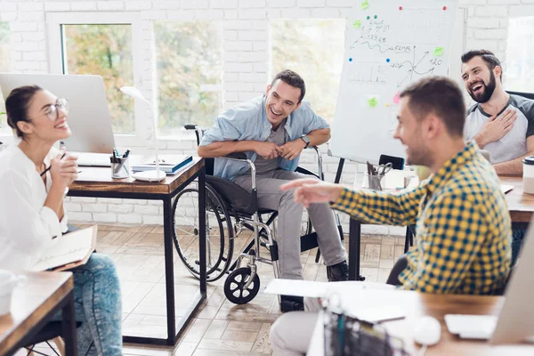 Lavoratori d'ufficio e uomo in sedia a rotelle discutono di momenti di lavoro in un ufficio moderno . — Foto Stock