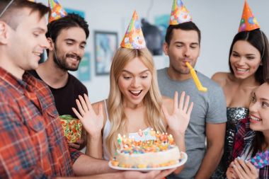 Doğum günü için bir pasta mumlar ile ile memnun olan bir kız. O onun zevk için Konuklar gösterir.