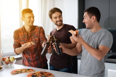 Erkek bira içmek ve mutfakta pizza yemek. Onlar konuşmak ve iyi eğlenceler.
