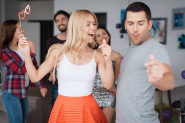 Bir erkek ve bir kadın ev bir partide dans ediyor. Neşeli ve mutlu görünüyorlar.