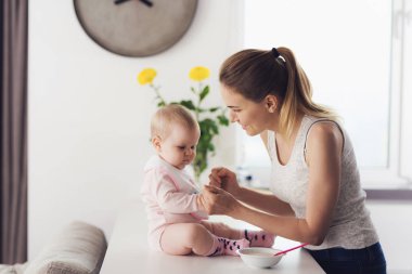 Anne ve bebek mutfakta. Kadın ile bebek maması bebek besleyecek.