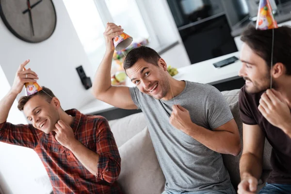 Los hombres se están poniendo un sombrero de cumpleaños. Se están preparando para una fiesta. . — Foto de Stock