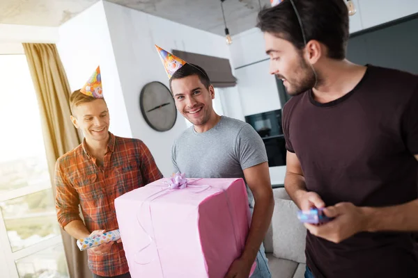 Männer mit Geburtstagsmützen zeigen einander Geschenke. — Stockfoto
