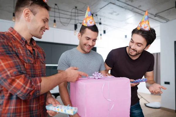 Hommes dans chapeaux d'anniversaire montrent à l'autre cadeaux . — Photo