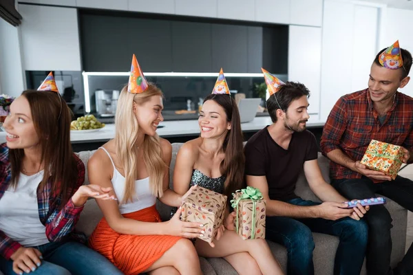 Fiesta en honor al cumpleaños. Los chicos y chicas están sentados en el sofá y conversando . — Foto de Stock